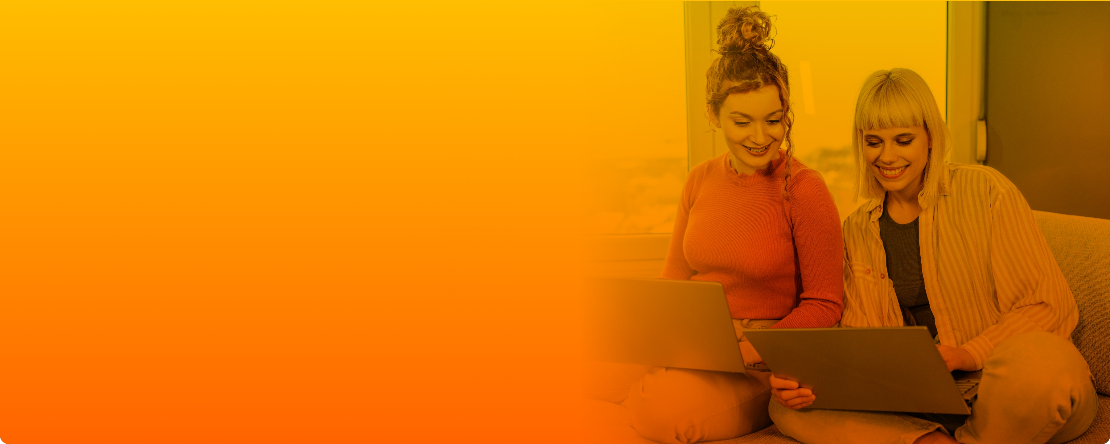 Zwei Frauen lächeln während sie auf den Laptop schauen.