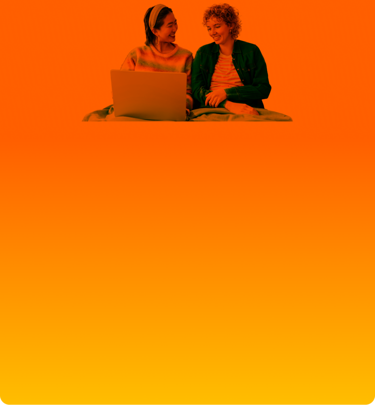 Gute Freundschaft zahlt sich aus! Zwei Frauen lächeln während sie auf den Laptop schauen.