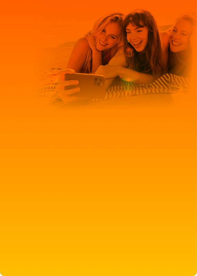 SIM-Karte Sommer-Deal: drei junge Frauen lächeln für ein Selfi auf einer Decke liegend in die Handykamera.