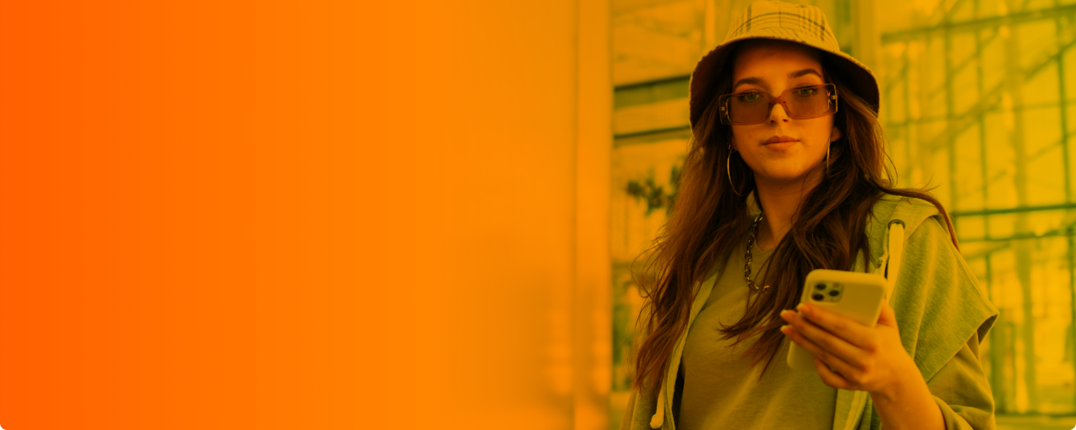 Eine junge Frau mit Sonnenbrille und Sonnenhut hält ihr Smartphone in der linken Hand und nutzt ihren Mobilfunktarif.