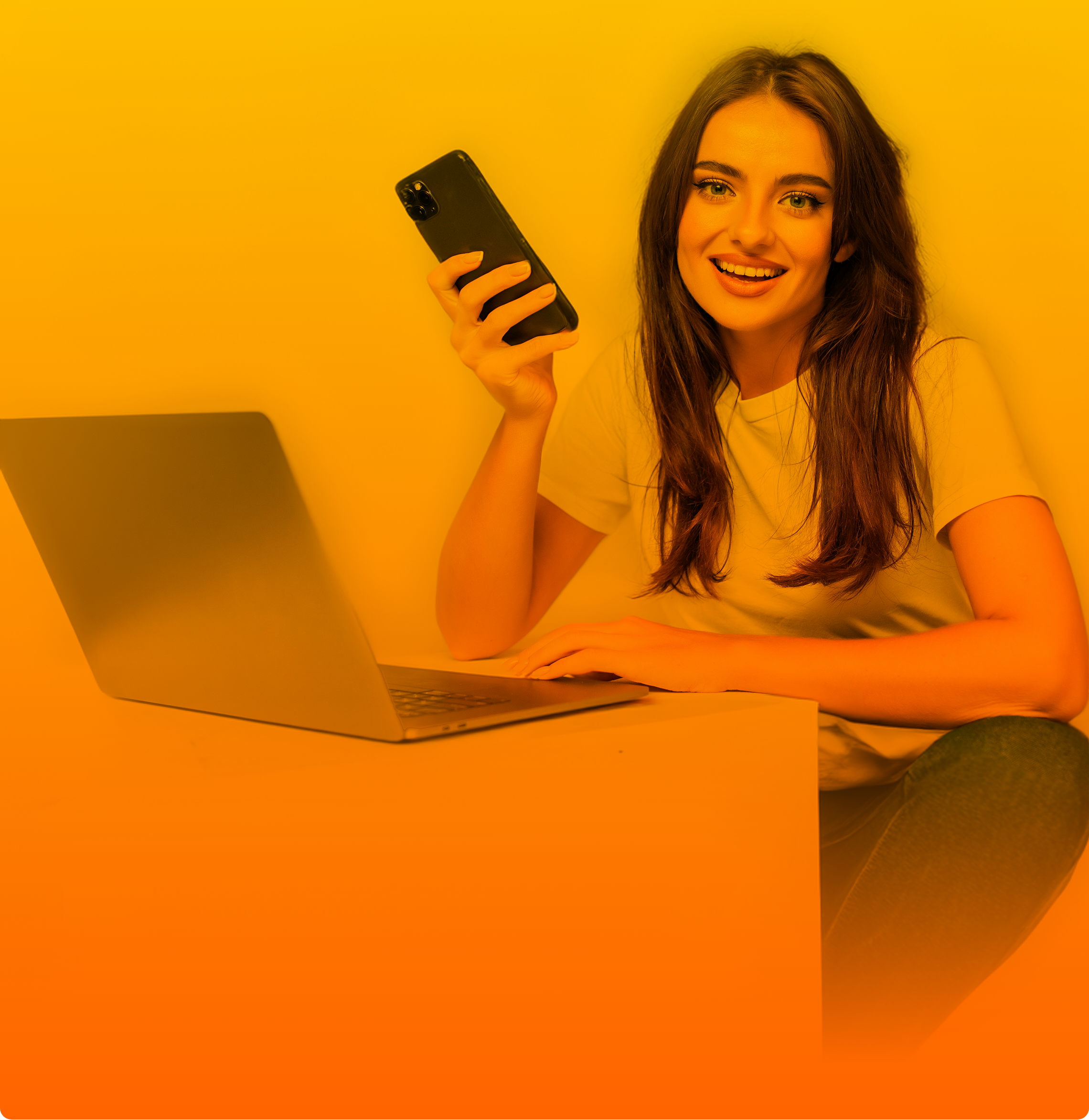 Am Tisch sitzende Frau mit Laptop und Handy, sucht nach einem Vertrag trotz Schufa für ihre Bedürfnisse.