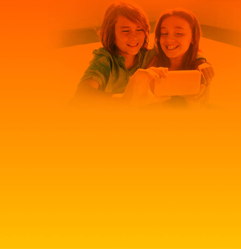 Zwei Kinder nutzen ein Handy mit passendem Kinder-Handytarif für ein Foto.